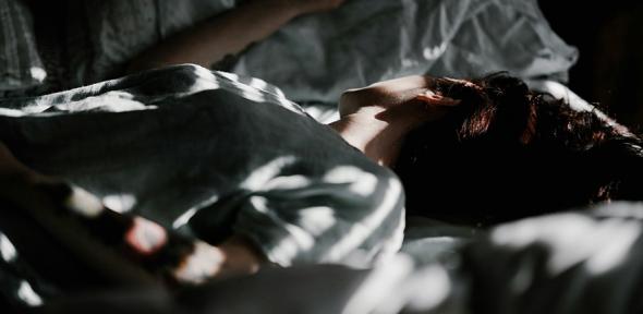 A person laying in a bed under a blanket