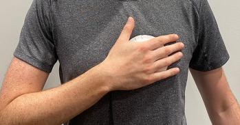 Person wearing a grey t-shirt holding a palm-sized device to their chest